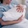 new-mother-in-hospital-gown-embraces-her-baby